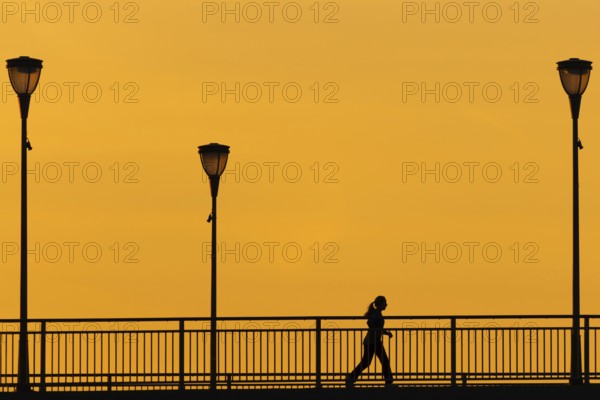 A jogger runs across the Old Bridge in Frankfurt am Main in the early morning shortly in front of