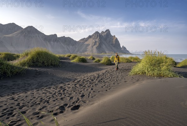 Tourist on a sand dune, Black beach with volcanic sand, Sand beach, Dunes with grass, Stokksnes
