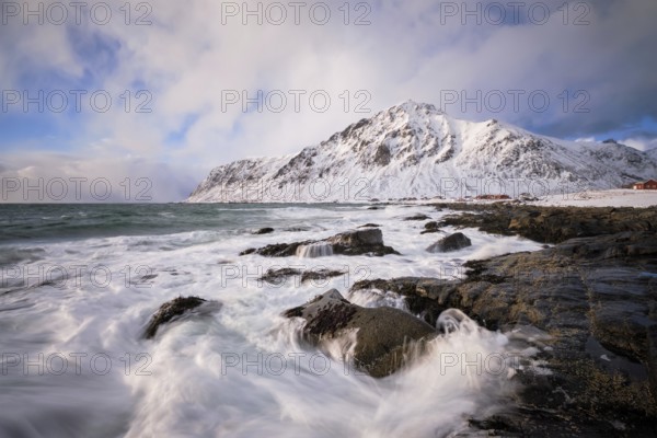 Beach of Norwegian sea on rocky coast in fjord on sunset in winter. Vareid beach, Lofoten islands,