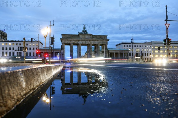The Brandenburg Tor is reflected in a puddle, cars with lights switched on, Berlin, 27.01.2025,