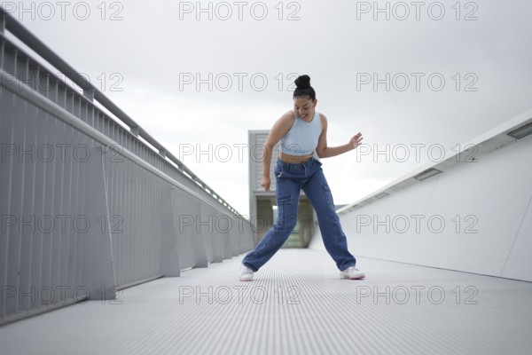 A woman in blue jeans is dancing on a white surface. Concept of freedom and joy as the woman