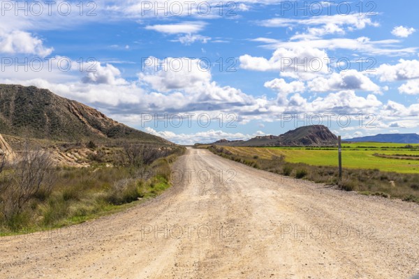 Scenic view of a gravel road stretching through the bardenas reales desert landscape under a bright