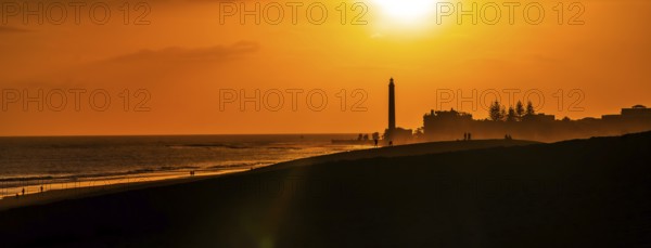 Tourists enjoying a beautiful sunset over maspalomas dunes in gran canaria, spain, with the iconic