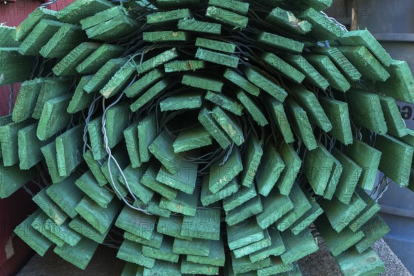 Close-up of rolled fluorescent green painted wood and steel wire snow fence in outdoor storage