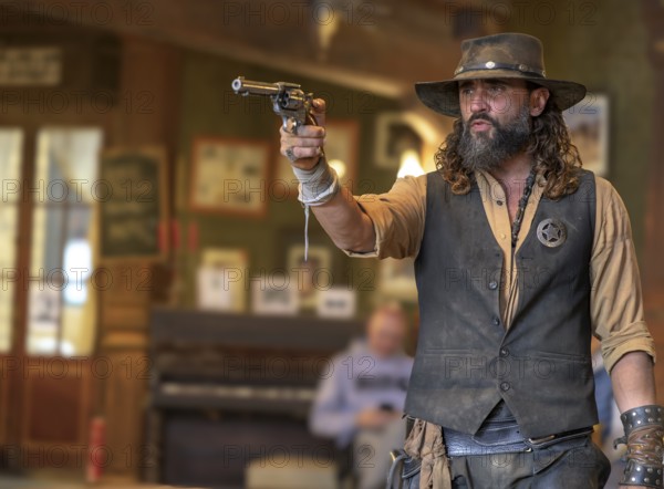 Western actor (sheriff with colt) in the saloon of the western village Fort Bravo or Texas