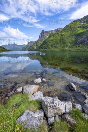 Small boats at the fjord Austnesfjorden, idyllic Norwegian fjord landscape, mountains reflected in