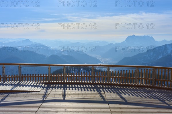 Wooden platform with a view of snow-covered mountains under a blue sky, Steinplatte, Waidring,