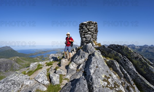 View of mountains and fjord landscape, mountaineer at the summit of Rundfjellet, Svolvaer,