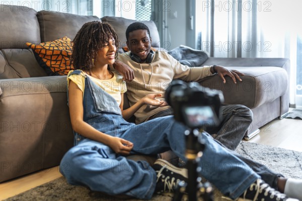 Two videomakers are creating content for their channel, discussing and smiling while recording a