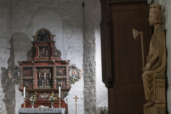 Richly decorated wooden altar in front of a stone wall, decorated with images of saints, wooden