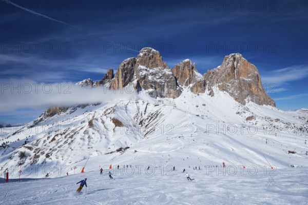 View of a ski resort piste with people skiing in Dolomites in Italy