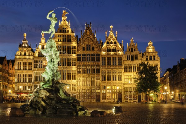Antwerp famous Brabo statue and fountain on Grote Markt square illuminated at night and old houses.