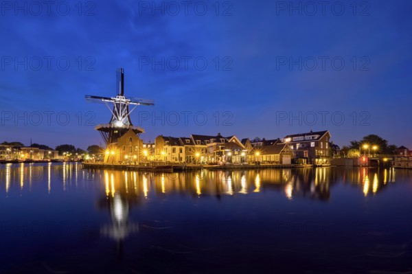 View of Harlem cityscape with landmark windmill De Adriaan on Spaarne river in the night