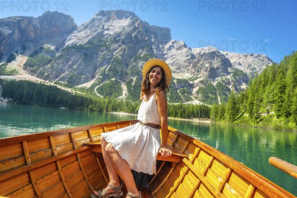 Young woman relaxing on a wooden rowboat at lake braies, enjoying the turquoise water and stunning