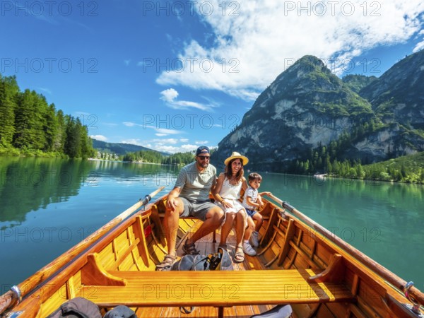 Family enjoying a sunny summer day rowing a wooden boat on the crystal clear waters of lake braies,