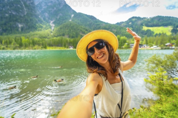 Happy tourist taking a selfie at lake dobbiaco with ducks swimming in the emerald green water and