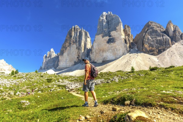 Hiker enjoying the breathtaking view of the tre cime di lavaredo peaks during a sunny summer day in