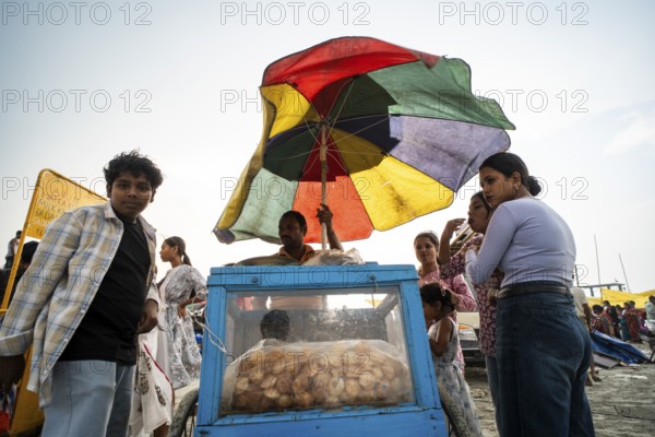 GUWAHATI, INDIA - APRIL 5: A vendor sells panipuri as he stand under a large umbrella during a pre