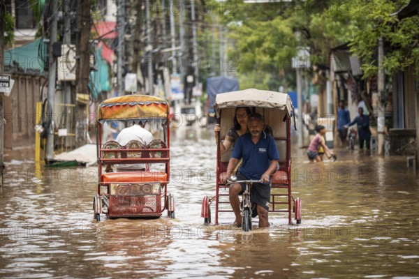 Commuters in cycle rickshaws as they wade through a flooded street after heavy rains in Guwahati,