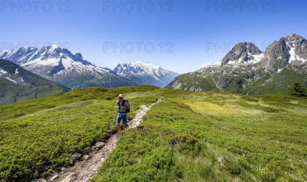 Mountaineer on hiking trail in front of mountain panorama with glaciated mountain peaks, Aiguille