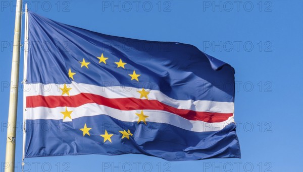 The flag of Cape Verde flutters in the wind, isolated against a blue sky