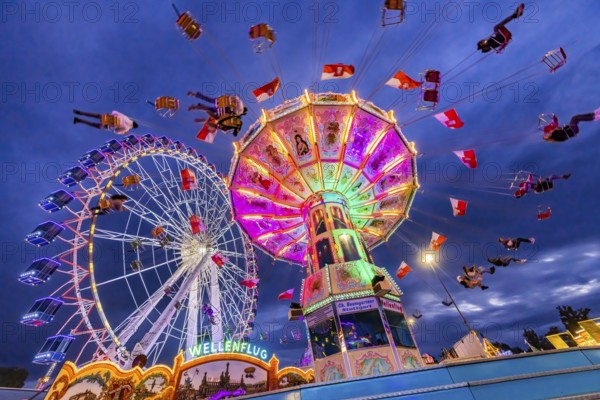 Chain carousel and Ferris wheel in the evening. 177th Cannstatter Volksfest at the Cannstatter
