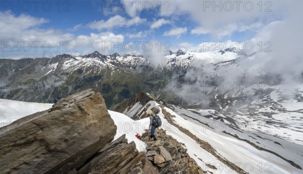 Mountaineer on a rocky ridge with snow, descent from the summit of Schönbichler Horn, view of