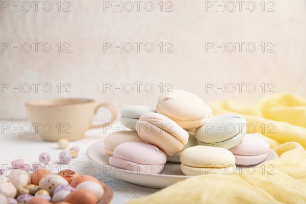 Colored zephyr or marshmallow with cup of coffee and dragees on white concrete background and