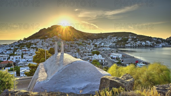 Agia Paraskevi Chapel, Small chapel at sunset with a view of a coastal town and the sea in the