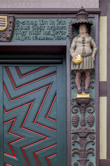 Detailed wooden door of a half-timbered house with statue and decorated façade, clear zigzag