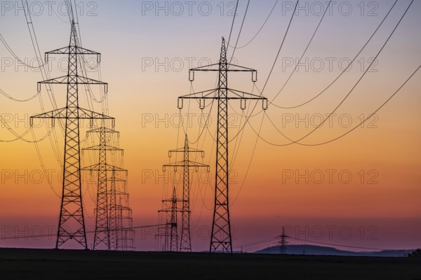 High-voltage pylons, overhead power lines at sunset. Schwieberdingen, Baden-Württemberg, Germany,