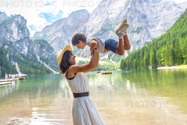 Happy mother lifting her son, enjoying summer vacation at lake braies - pragser wildsee - in the