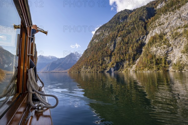 A trumpet is played on the echo wall of a tourist boat, Königssee, autumnal mountain landscape