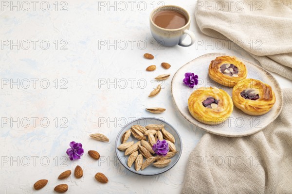 Small cheesecakes with jam and almonds with cup of coffee on a white concrete background and linen