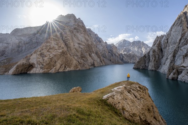 Tourist at the blue mountain lake between rocky steep mountain peaks, Sun Star, Kol Suu Lake, Sary