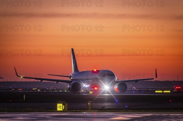 Early in the morning in front of sunrise at the airport, a Lufthansa aircraft stands ready for