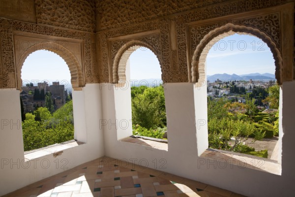 Arched decorated Moorish stone windows looking over gardens, Generalife garden, Alhambra, Granada,