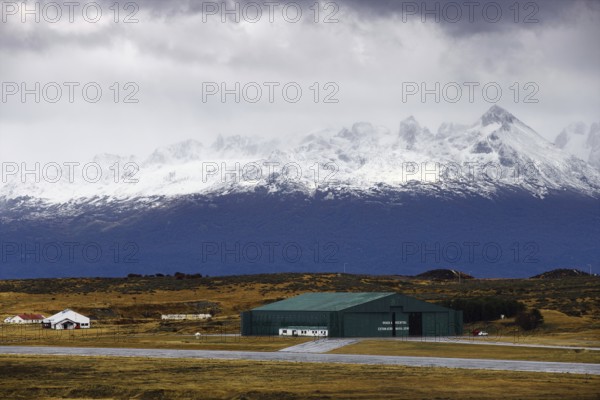 View from the deck of the cruise ship to an industrial hall in front of a snow-covered mountain