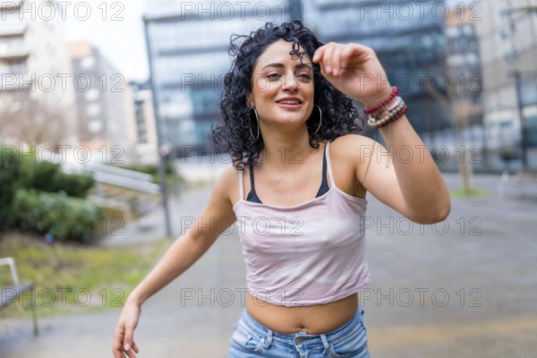 Carefree young latin woman enjoying dancing outdoors in urban environment, expressing joy and