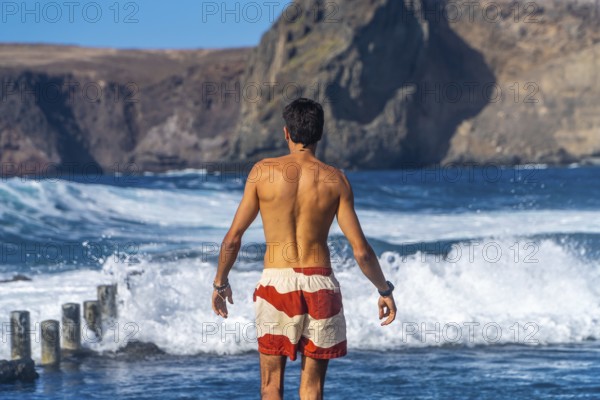 Tourist admiring the ocean waves in the natural pools of agaete, a charming coastal town in gran