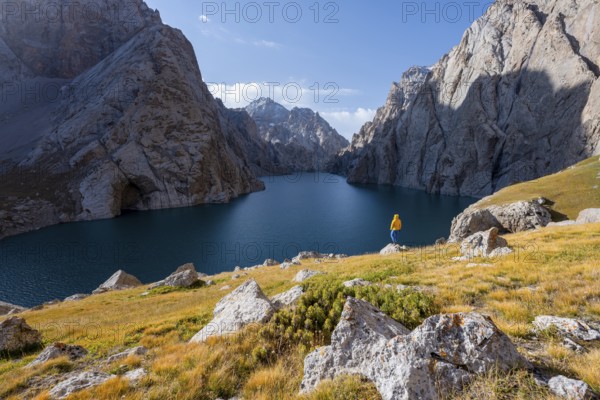 Tourist at the blue mountain lake between rocky steep mountain peaks, Kol Suu Lake, Sary Beles
