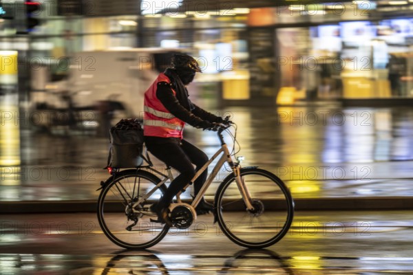 Street at the central station, cyclist, rainy weather, city centre, in the evening, Essen, North