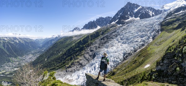Mountaineer standing on a rock, mountain landscape with glacier Glacier des Bossons and summit of