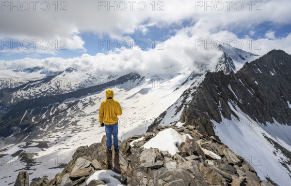 Mountaineer at the summit of the Schönbichler Horn, view of snow-covered mountain landscape with