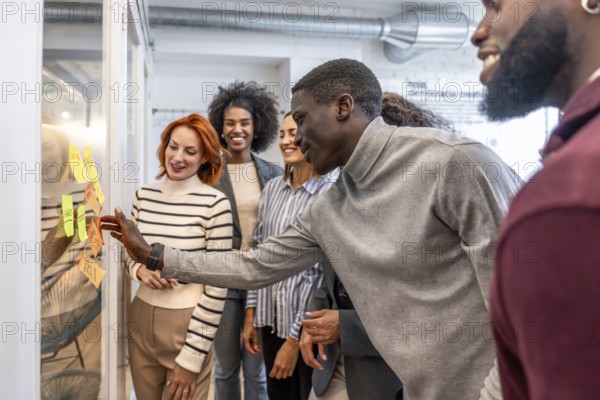 African man participating in a brainstorming process in a startup standing with colleagues at the