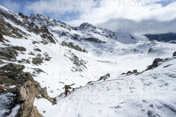 Mountaineer with skis climbing up a steep snow slope to the fork Porta d'Es-cha, ski tour Bündner