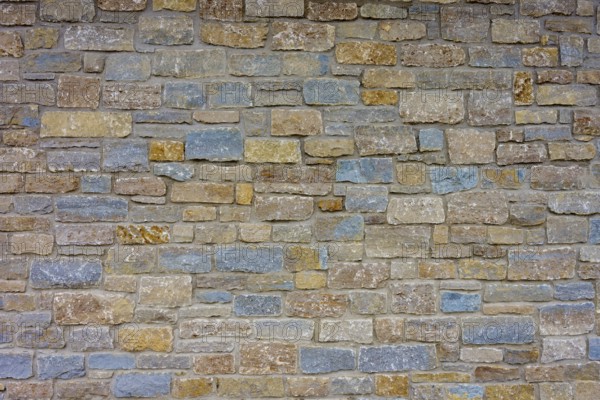 Wall of colourful natural stones in shades of blue and beige with uneven texture, Würzburg,