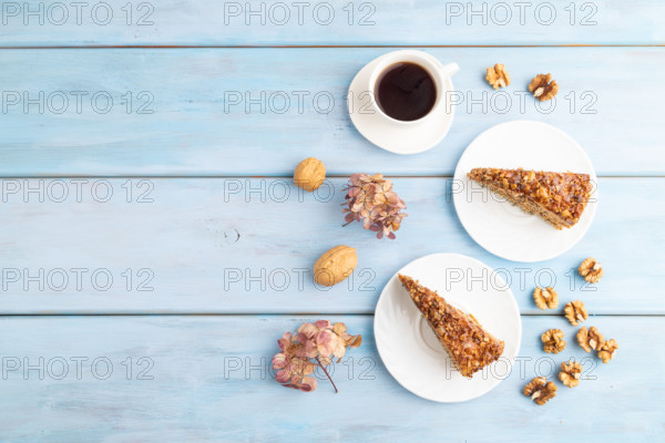 Walnut and hazelnut cake with caramel cream, cup of coffee on blue wooden background. top view,