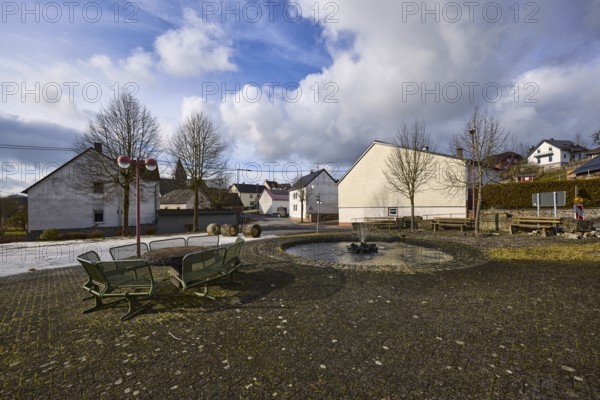 Village fountain, benches, lantern, trees, houses, blue sky, cumulus clouds, cirrostratus clouds,