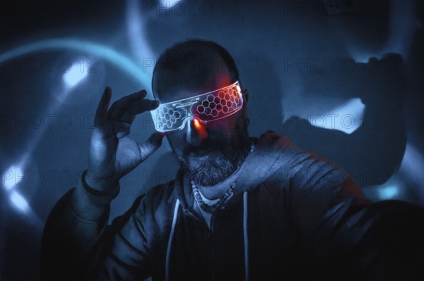 Bearded man adjusting futuristic glowing smart glasses in dark cyberpunk setting with blue and